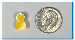 A yellow tab battery next to a dime for size comparison.